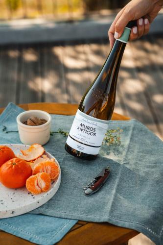 a bottle of wine and a plate of oranges on a table at Quinta da Torre - Anselmo Mendes