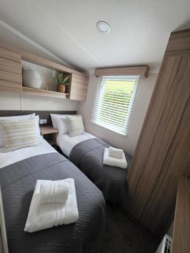 a bedroom with two beds with white pillows at 'By The Stream' 60 The Beeches in Prenteg