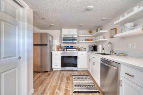 Una cocina con gabinetes blancos y electrodomésticos de acero inoxidable. en Stay Portland - Vibrant Portland Getaway, Chic Flat, en Portland