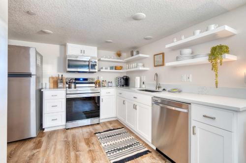 Una cocina con gabinetes blancos y electrodomésticos de acero inoxidable. en Stay Portland - Vibrant Portland Getaway, Chic Flat, en Portland