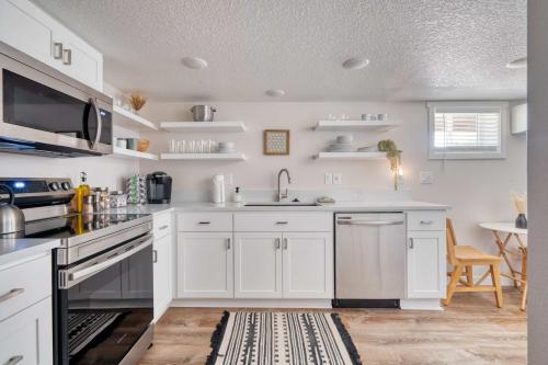 a kitchen with white cabinets and a sink at Stay Portland - Vibrant Portland Getaway, Chic Flat in Portland