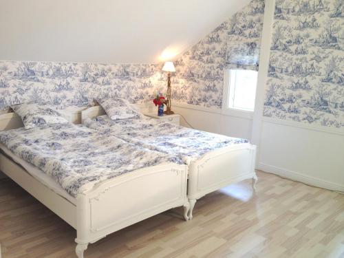 1 cama blanca en un dormitorio con papel pintado azul y blanco en Villa Granvik, en Söderfors