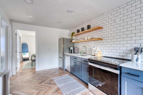 a kitchen with blue cabinets and a white brick wall at Stay Portland - The Woodstock Inn - Reed College & Vintage Shops in Portland