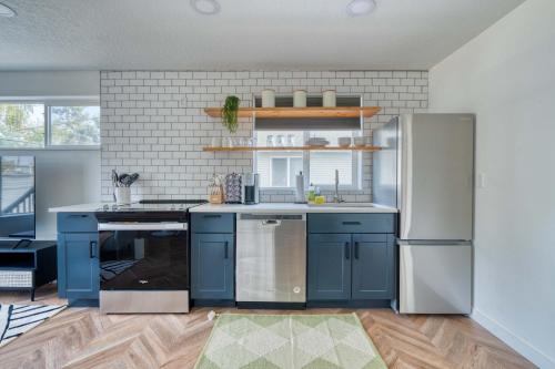 Stay Portland - The Perfect Artist's Retreat in Woodstock في بورتلاند: مطبخ مع خزائن زرقاء وأجهزة حديد قابلة للصدأ