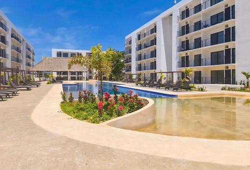 a large apartment building with a swimming pool and flowers at Departamento Comodo con Alberca a 10min de la Playa in Mezcales
