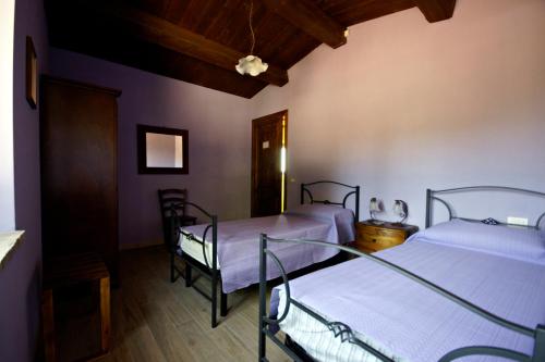 two beds in a room with purple walls and wooden floors at Locanda della Rocca in Sarnano