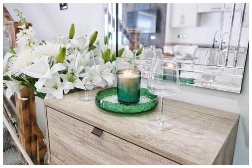 a table with glasses and a candle and flowers at 1Bed Apt- Sleeps 6 City Center Jacuzzi Bath Wifi in Bradford