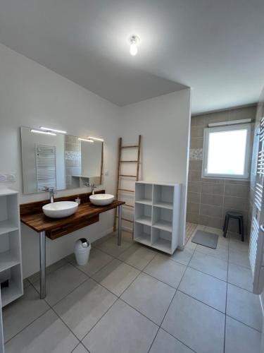Un baño con dos lavabos y un espejo. en Gîte neuf, à 12mn du Futuroscope, à la campagne -Le Trèfle, en Saint-Léger