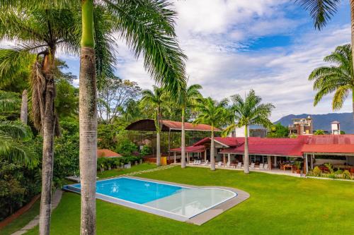 an exterior view of a house with a swimming pool and palm trees at Altavista Casahotel - Asociado Casa Andina in Moyobamba
