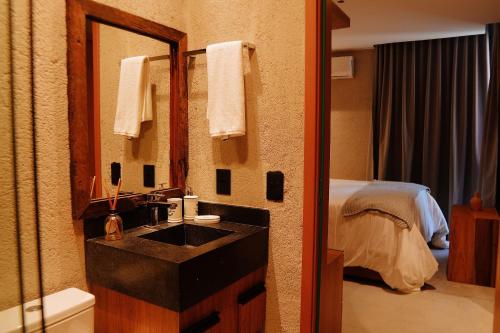 une salle de bain avec un lavabo, un miroir et un lit dans l'établissement Casa Pé na Areia | Rooftop, 5 suítes, piscina, à Barra do Camaragibe