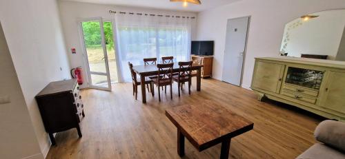 a living room with a table and chairs and a television at Le Clos Beau Jardin in Gaillan-en-Médoc