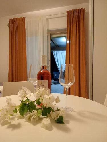 a table with two wine glasses and flowers on it at Costa degli Dei apartment in Pizzo