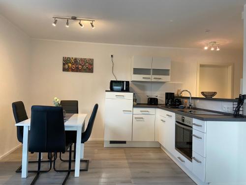 a kitchen with white cabinets and a table with chairs at FeWo Diemelblick in Diemelsee