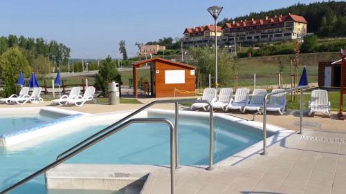 a swimming pool with chairs and a building at Casa Lara Apartman in Egerszalók