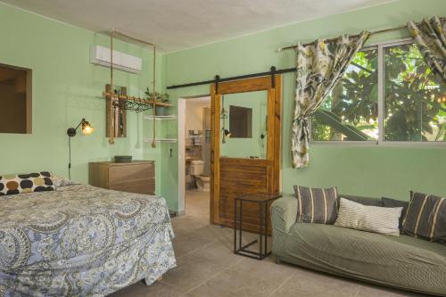 a bedroom with a bed and a couch and a window at Cabarete Boutique Kite Hotel Garden Loft in Cabarete
