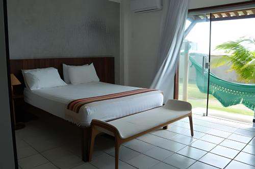 a bed with a bench in a room with a window at Casa Bruma |Pé na areia, encontro do rio com o mar in Francês