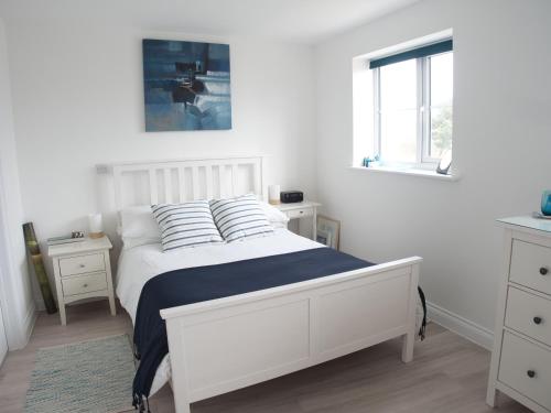 a white bedroom with a white bed and a window at Petralia BnB in Portland