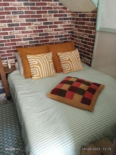 a large bed with pillows and a brick wall at Room - Les loups bleus in La Burbanche