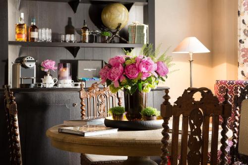 a table with a vase of pink flowers on it at Les Tournelles in Paris