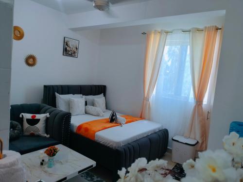 a bedroom with a bed and a couch and a window at Cutie Coastal Studio in Mombasa