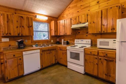 una cucina con armadietti in legno ed elettrodomestici bianchi di Frio Country #20 a Concan