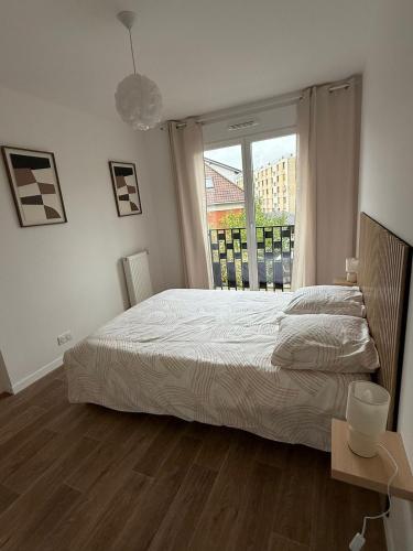 a bedroom with a bed and a large window at Un cocon neuf et lumineux aux portes de Paris in Champigny-sur-Marne