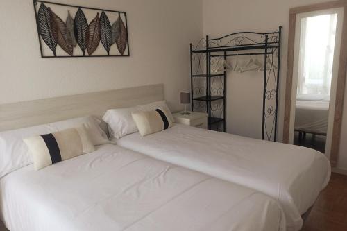 a bedroom with two beds with white sheets at Apartamento con gran terraza in San Vicente de la Barquera