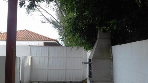 a white fence next to a white garage at Casa aconchegante próxima a praia in Laguna