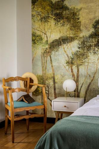 a bedroom with a chair and a wall mural at L'écrin des Gaves in Hastingues