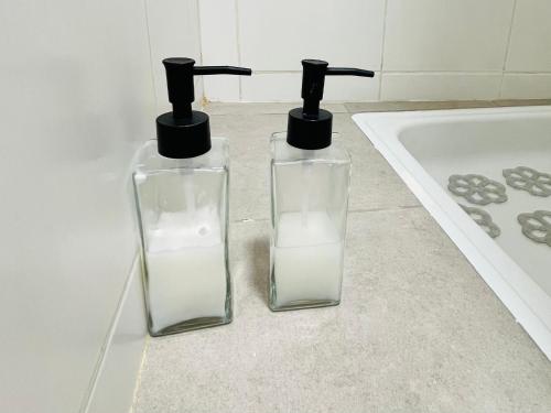 two glass bottles sitting on a counter next to a bath tub at Studio Conexión Mendoza ubicación ideal, WiFi rápido y cerca del Parque San Martín y Av Arístides in Godoy Cruz