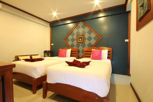 a bedroom with two beds with white sheets and pink pillows at TR Guesthouse in Sukhothai