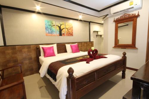 ein Schlafzimmer mit einem großen Bett mit rosa Kissen in der Unterkunft TR Guesthouse in Sukhothai