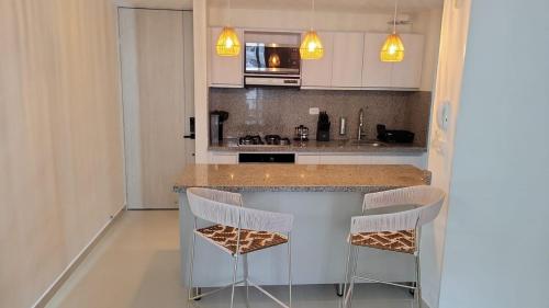 a kitchen with a counter and two stools at Centro Historico Barranquilla New 3BR Apt w Pool in Barranquilla