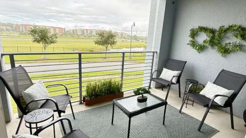 a balcony with chairs and tables and a view of a field at Stay Our Stylish 2 Br, 6 Minutes To Disney World in Kissimmee