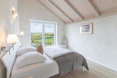 a white bedroom with a bed and a window at Schimmelreiter in Struckum
