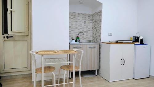 a small kitchen with a table and a refrigerator at Roca House in Valenzano