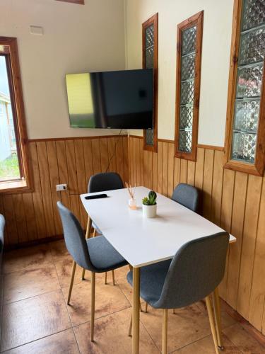a table with chairs and a tv on a wall at Cabañas dunn in Puerto Cisnes