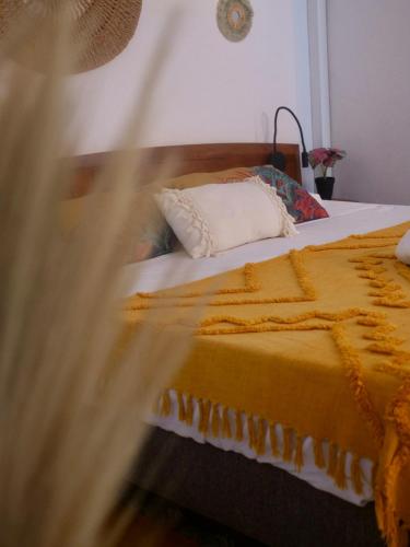 une chambre avec un grand lit avec une couverture jaune dans l'établissement L'oasis, à Grand-Bourg