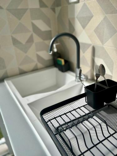 a kitchen sink with a kitchen utensils on a drying rack at L'oasis, appartement proche plage privée in Grand-Bourg