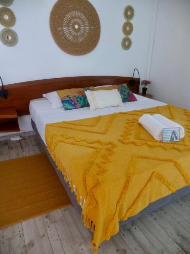 a bedroom with a large bed with a yellow blanket at L'oasis, appartement proche plage privée in Grand-Bourg