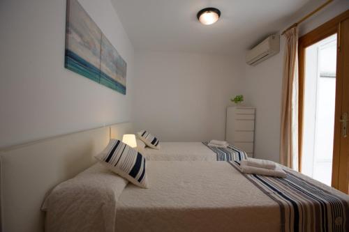 two beds in a white room with a window at Harmony Seafront 365 by Can Ventet in Port de Pollensa