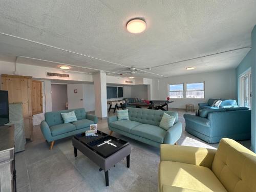 a living room with blue couches and a table at Beachfront Condo, Ocean Views, Near Patrick SFB in Satellite Beach