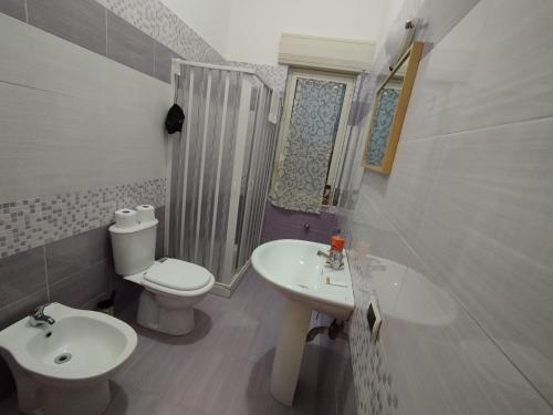 een badkamer met een wastafel, een toilet en een spiegel bij GiGi Affittacamere in Siracusa