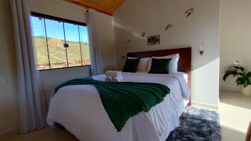 a bedroom with a large bed with a window at Refúgio na Serra dos Garcias in Aiuruoca
