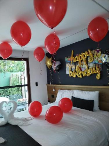 een bed met rode ballonnen en een bordje met 'Happy Birthday' bij Elite Maya Hotel & Spa in Antigua Guatemala