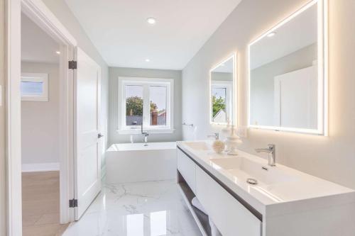 a white bathroom with a sink and a tub at Prestige 3BR Luxury Living in Queen West in Toronto