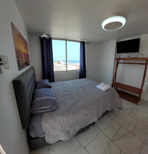 a bedroom with a bed and a couch and a window at Bravos Hospedaje Punta Negra in Punta Negra