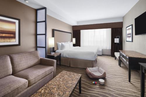 a hotel room with a bed and a couch at Best Western Premier Freeport Inn Calgary Airport in Calgary