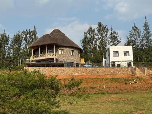 a building with a thatched roof on top of a field at African-style villa with lake view, sleeps 12 in Rwamagana