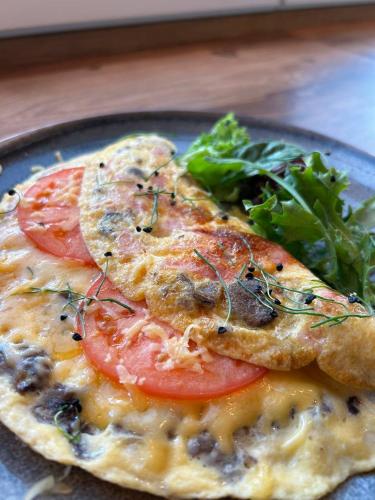 Una pizza con tomates y verduras en un plato. en Wellotel Chornomorsk, en Chornomorsk